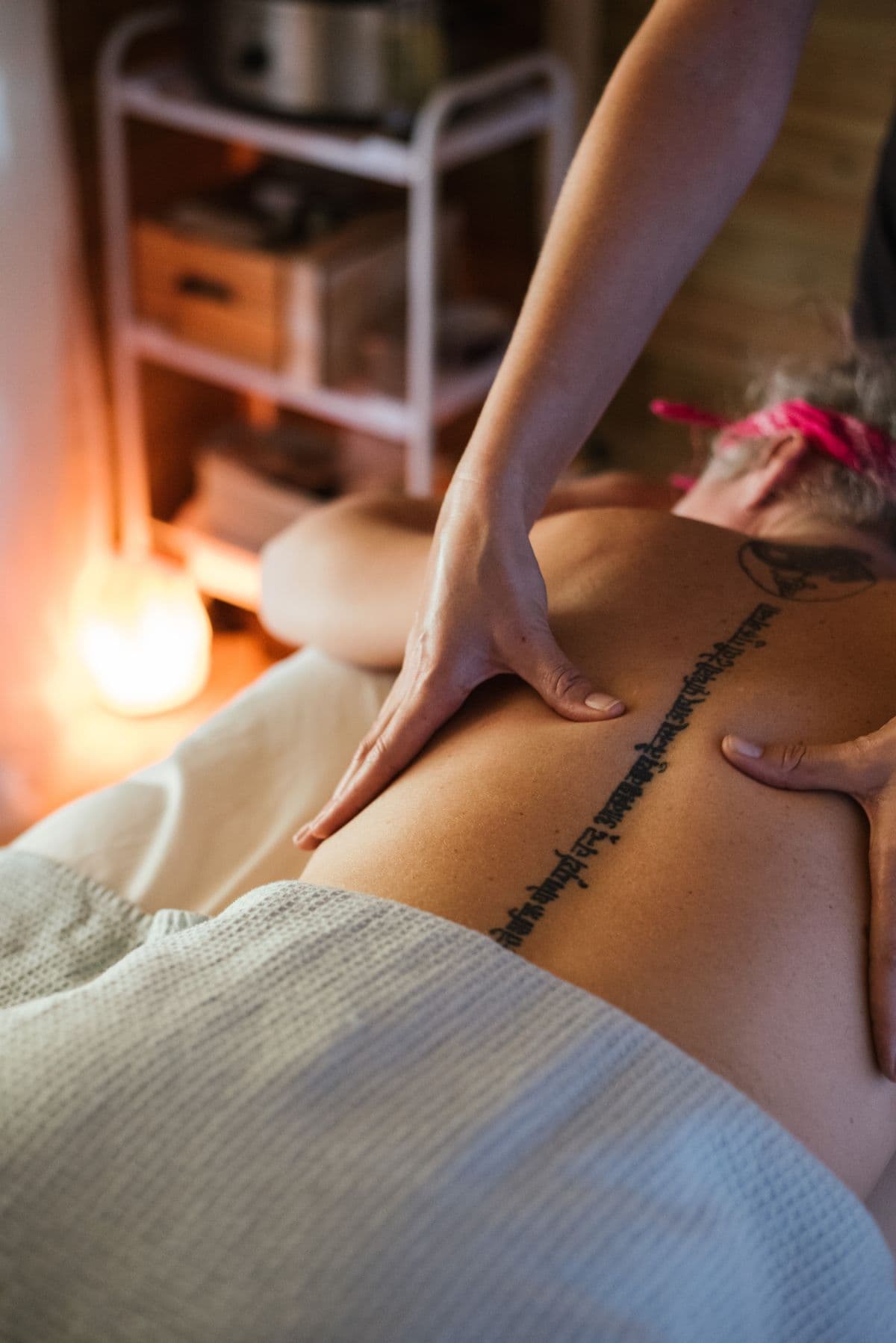 Two hands working a back massage in synchronized four-hands style